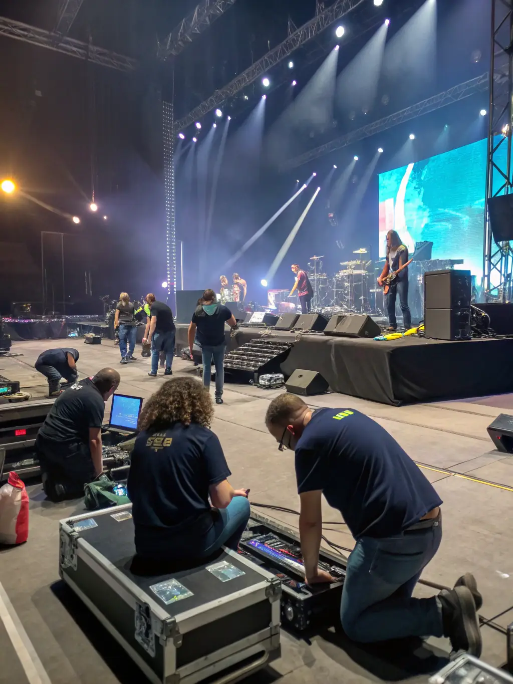 A photo of a KERMHIT ASSO volunteer helping set up equipment for a concert, showcasing the organization's hands-on approach.